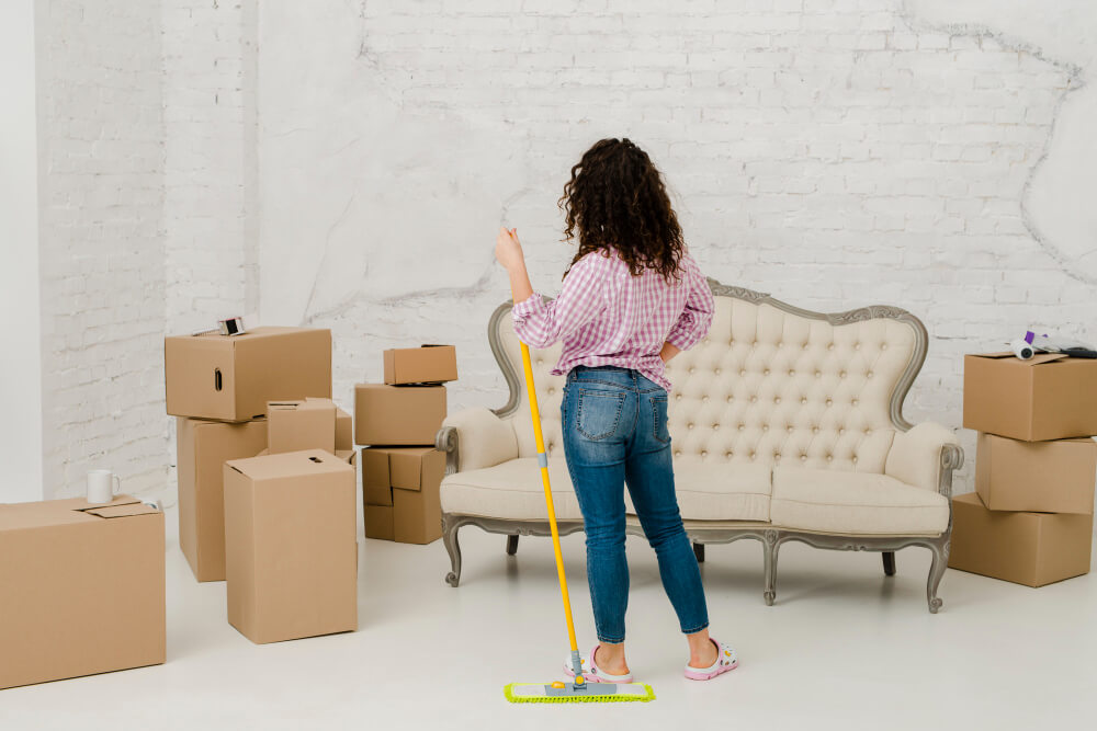 a woman looking at the stacks of boxes while holding a mop